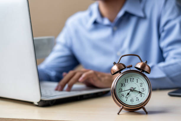istock Close up alarm clock with young Businessman using laptop analysis marketing plan and drinking coffee in the morning. Business, Finance and lifestyle concepts 1150415273