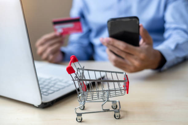 close up mini cart, Asian businessman holding credit card using laptop and smart phone for online shopping while making orders. internet, technology, ecommerce and online payment concept cerrar mini carrito, comerciante asiático con tarjeta de crédito usando el ordenador portátil y el teléfono inteligente para las compras en línea, mientras que hace pedidos. internet, tecnología, comercio electrónico y concepto de pago en línea