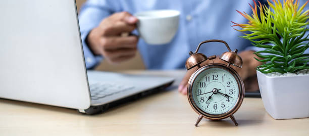 istock Close up alarm clock with young Businessman using laptop analysis marketing plan and drinking coffee in the morning. Business, Finance and lifestyle concepts 1150416057
