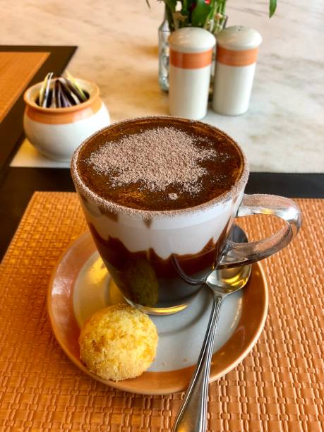 imagen de taza de chocolate caliente con crema, azúcar glas espolvoreada, espolvoreado de cacao y torta de galletas de macaroon, taza y platillo en mesa naranja, bebida de chocolate caliente en café/cafetería, té de la tarde para dos tomar un descanso - espresso coffee cream coffee shop fotografías e imágenes de stock