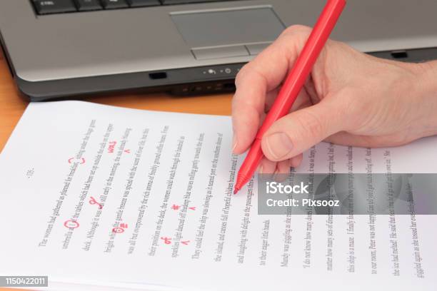Hand Proofreading A Manuscript Beside Laptop Stock Photo - Download Image Now - Editor, Proofreading, Paper