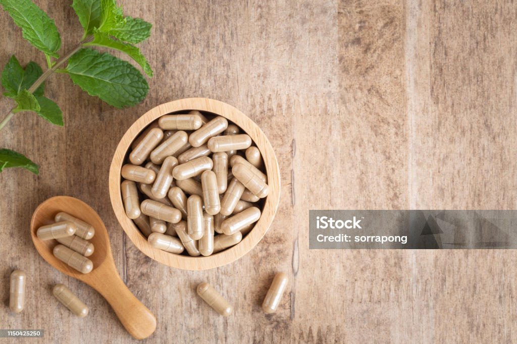 Herbal capsules  in cup on wooden table background . Top view of medicine for healthy and capsules on the spoon wooden Nutritional Supplement Stock Photo