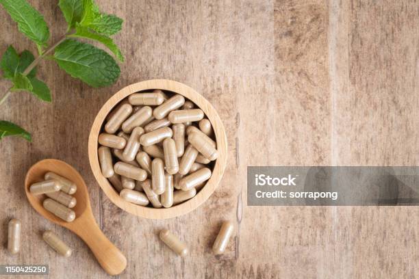 Herbal Capsules In Cup On Wooden Table Background Top View Of Medicine For Healthy And Capsules On The Spoon Wooden Stock Photo - Download Image Now