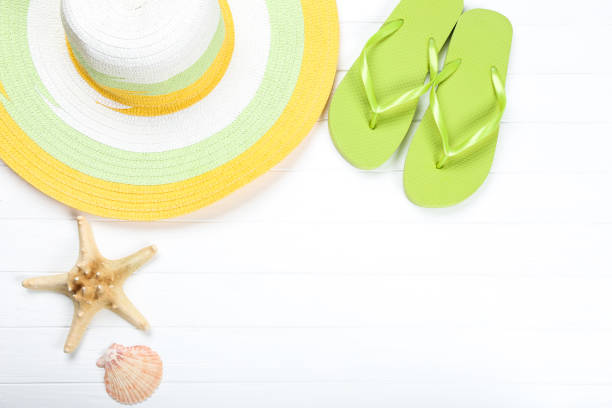 istock Pair of flip flops with seashells and hat on white wooden table 1150426577