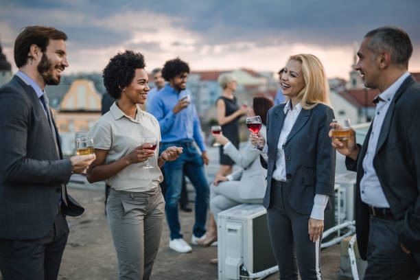 istock Happy business people talking while drinking alcohol on a rooftop party. 1150427728