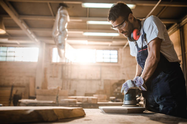 istock Young man using sander while working on a piece of wood in a workshop. 1150430931