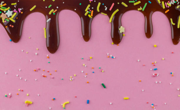 istock Chocolate cake topping sprinkles with chocolate flowing down on pink background 1150431139