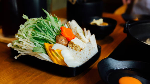 istock Sukiyaki vegetables set including cabbage, false pak choi, carrot, shiitake, enokitake, tofu, pumpkin, scallion and konjac noodle in black plate. 1150433596