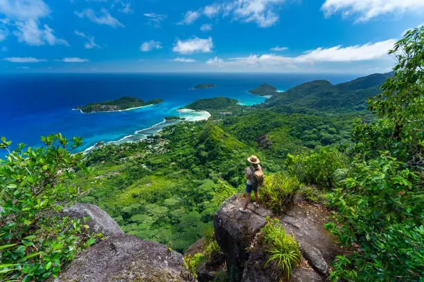 female hiker woman tourist standing high above indian ocean on tropical island of seychelles mahe enjoying amazing view