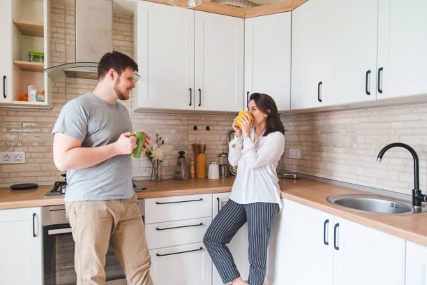 istock smiling man with woman at kitchen drinking tea 1150436004