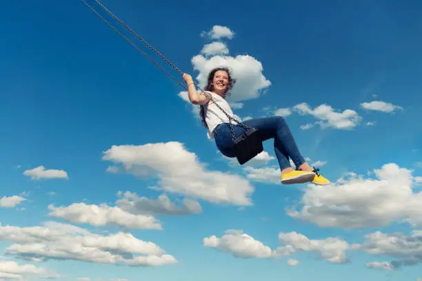 Photo of Young Adult Woman Swinging Against Blue Sky