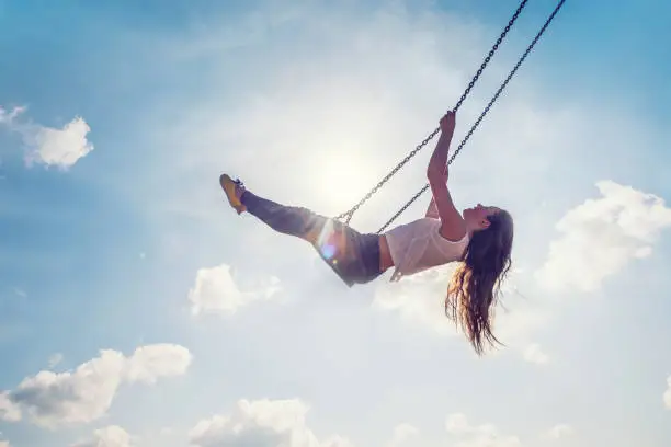 Photo of Young Adult Woman Swinging Against Blue Sky