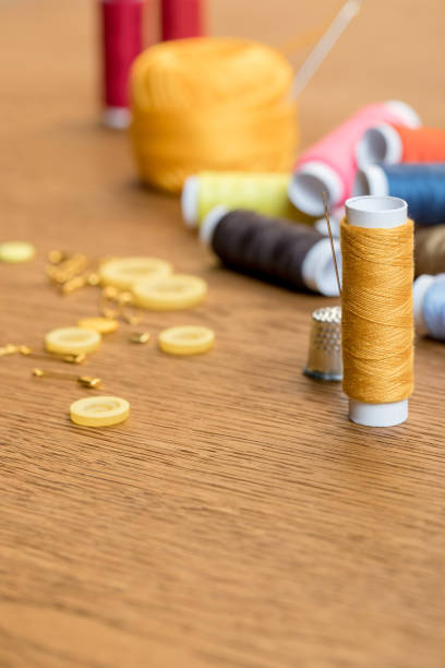istock selective focus of thimble and yellow thread coil with needle on wooden table with copy space 1150452382