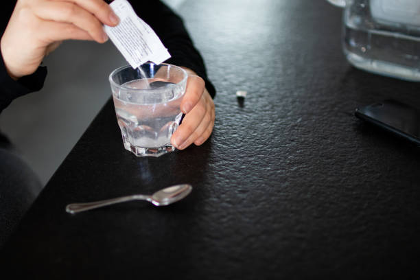 Woman dissolves medicine with soluble sachet in a water. stock photo
