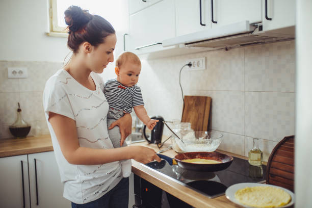 istock Single mother working at kitchen. Young mother making pancakes. 1150454901