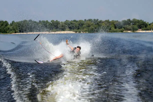 Happy asian man riding water skis on lake in summer and fall down