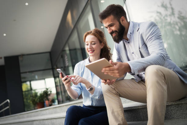 istock Two smiling young business people working on tablet outdoors 1150455166