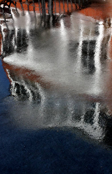 istock Old restored building facade, cast iron balconies reflected on wet street flooring. 1150458448
