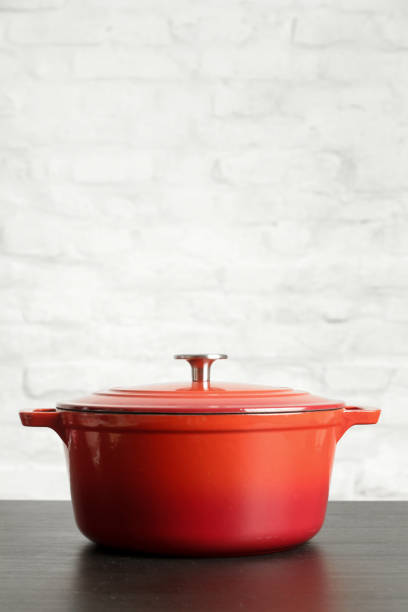 istock Red enameled saucepan against a white brick wall with copy space 1150459041