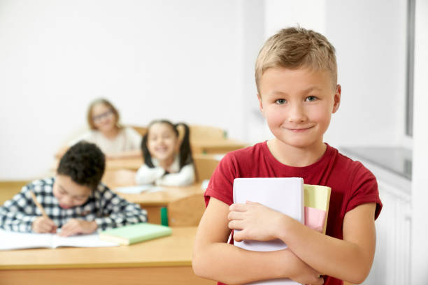 istock Schoolboy holding books, looking at camera, smiling. 1150459320
