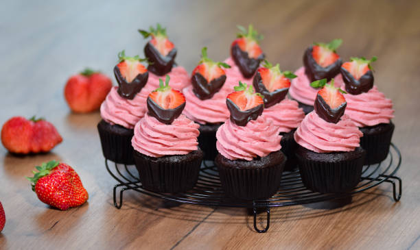 Fresh chocolate cupcakes in cup with pink icing on decorative background