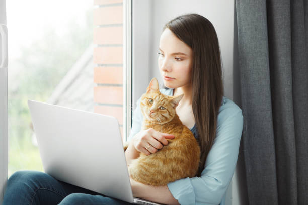 istock Thoughtful woman read information on notebook holding red pussy cat 1150461995
