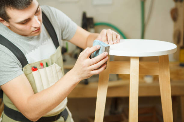 istock Carpenter polish round chair in workshop. Woodworker in apron 1150464881