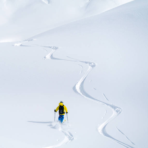 perspective aérienne d’un skieur de poudre descendant la pente immaculée - ski track powder snow track snow photos et images de collection