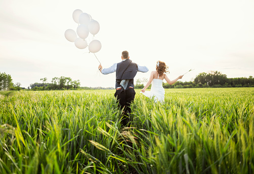 Couple just married celebrate their love, running through wheat field