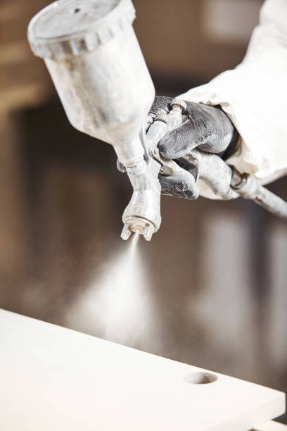 istock Vertical close-up of industrial worker using paint gun or spray gun for applying paint, airless spraying. 1150467507