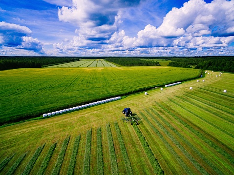 Aerial view of Tractor mowing green field in summer Finland.