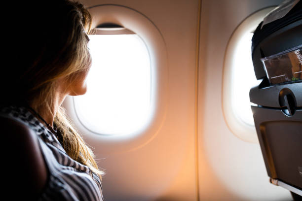 istock Happy woman enjoying while looking through plane window. 1150469643