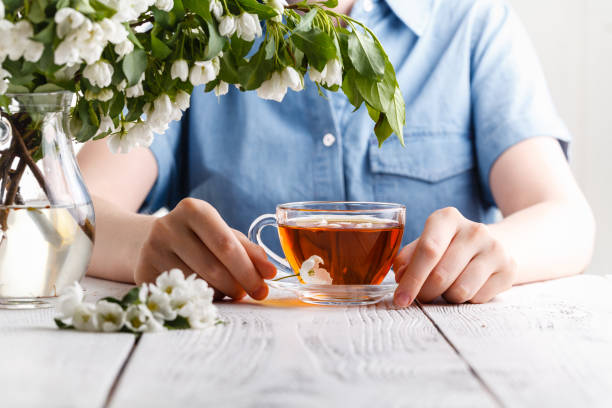 istock Girl having a cup of tea on table covered with apple tree flowers 1150469754