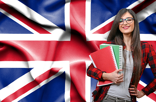 Happy female student holdimg books against national flag of Great Britain