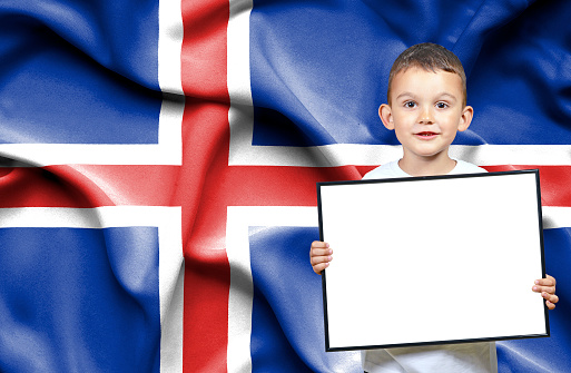 Cute small boy holding emtpy sign in front of flag of Iceland