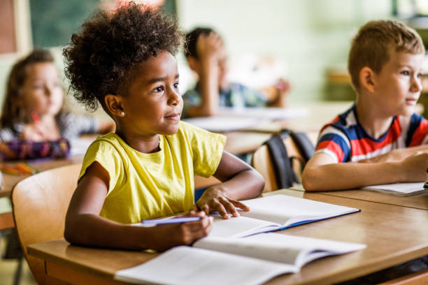 Paying attention a class at elementary school! School kids paying attention on a class in the classroom. Focus is on black girl. primary school exams stock pictures, royalty-free photos & images