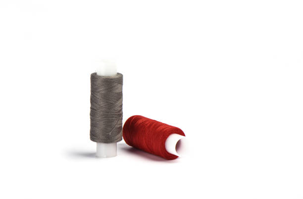 istock Cotton red and gray threads on the plastic sleeve for the sewing machine. 1150472082