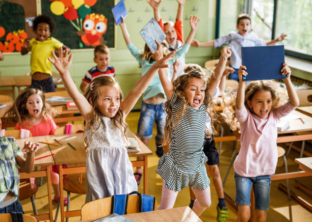 istock Large group of joyful elementary students jumping in the classroom. 1150472141
