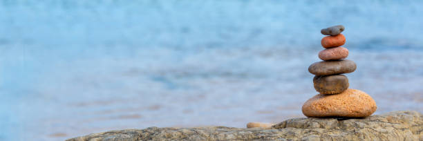 istock Pile of pebbles on a beach, panoramic blue water background 1150475406