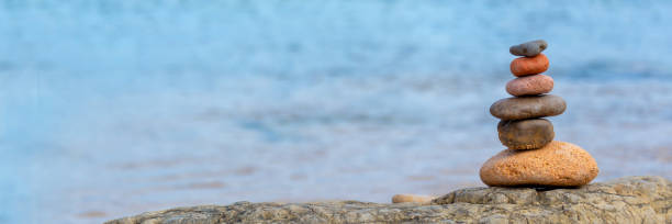 куча гальки на пляже, панорамный синий фон воды - stone balance pebble stack стоковые фото и изображения