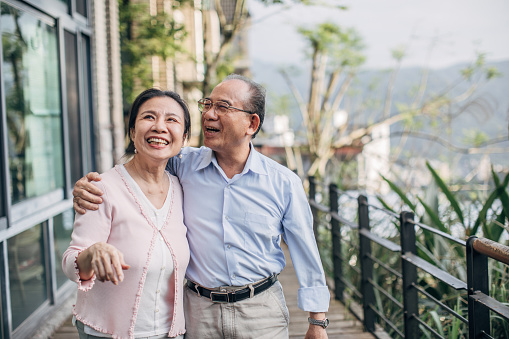 Man and woman, senior married couple standing on terrace at home together.