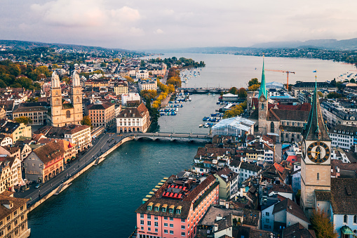 Aerial view of Zurich, Switzerland. Taken from a drone overlooking the Limmat River. Beautiful blue sky with dramatic cloudscape over the city. Visible are many traditional Swiss houses, bridges and churches.