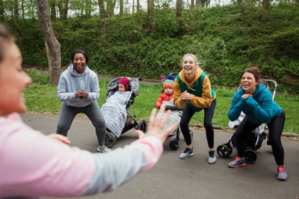 Fitness With Friends A group of mothers are doing a fitness bootcamp in the park with their babies in prams. baby squatting stock pictures, royalty-free photos & images
