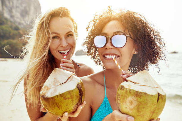 istock Two young women drinking from coconuts on a tropical beach 1150483011