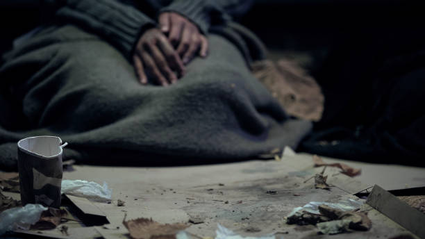 vagabondo coperto di coperta sporca seduta sul cartone, che vive per strada, rifugiato - slum living foto e immagini stock