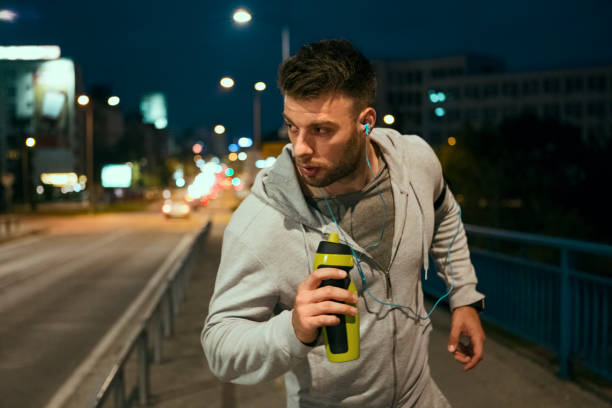 istock Young man jogging through the city at night 1150487761