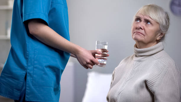istock Dissatisfied elderly woman refusing pills from medical worker, nursing home 1150487885