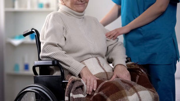 enfermera cuidando de la anciana en silla de ruedas cubierta por una manta, hospital - women middle aging process covering fotografías e imágenes de stock