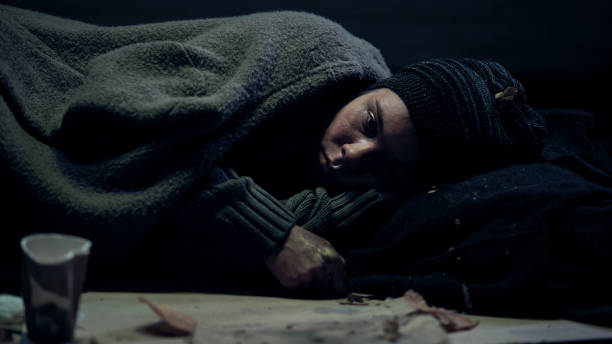 istock Depressed refugee lying on street feeling cold covered with dirty blanket, bum 1150488093