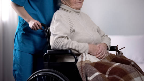 voluntario cuidando de la anciana en silla de ruedas cubierta por una manta - women middle aging process covering fotografías e imágenes de stock